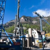 A bustling construction site with cranes against the picturesque Swiss Alps backdrop.