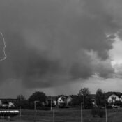 Monochrome image capturing a dramatic lightning strike during a thunderstorm over a neighborhood.