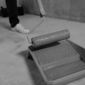 Black and white close-up of a paint roller and tray during a home renovation.