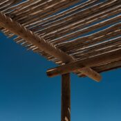 An artistic perspective of a wooden pergola with a deep blue sky backdrop, showcasing natural materials.