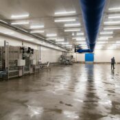Spacious warehouse interior with machinery and a person inspecting the facility.