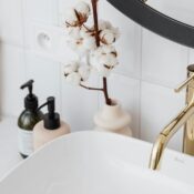 A stylish bathroom with a gold faucet, cotton plant, and modern accessories.