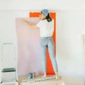 A woman applying wallpaper on a wall for home renovation indoors.