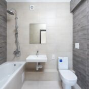 A contemporary bathroom features a bathtub, sink, and toilet with wood accents.