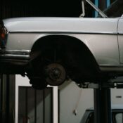 A classic car is elevated on a lift in a professional auto repair garage, showcasing its undercarriage.