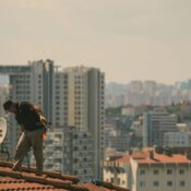 Construction worker on a rooftop in İstanbul with city skyline in the background.