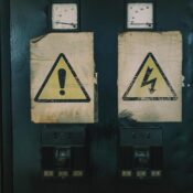 Close-up of industrial warning signs on an aged electrical panel.