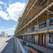Scaffolding on building facade at urban construction site under bright blue sky.
