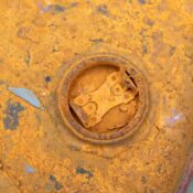 Detailed close-up of a rusty oil barrel with peeling orange paint texture.