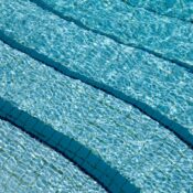 A detailed view of crystal clear swimming pool water over a tiled surface, showcasing its calm and refreshing nature.