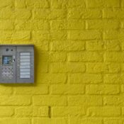 A vibrant yellow brick wall featuring a modern intercom system, ideal for security or design concepts.