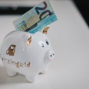 A white piggy bank with a €20 note inserted, symbolizing savings.