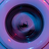 A washing machine spinning clothes under vibrant purple and blue lights.