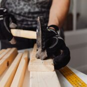 Craftsman hammering nails into wood, showcasing woodworking skills and tools in action.