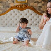A mother and her baby sitting on a bed preparing for a special occasion together.