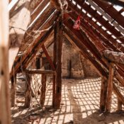 Interior view of wooden framing and rafters in a partially constructed attic space, highlighting a rustic and textured structure.