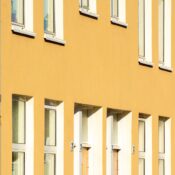 Bright yellow building facade with multiple windows and sunlight shadows.