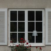 White window with shutters and blooming red roses outside a house in Jönköping, Sweden.