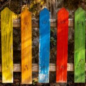 Vivid multi-colored wooden fence planks create a striking visual pattern outdoors.