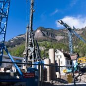 A bustling construction site with cranes against the picturesque Swiss Alps backdrop.