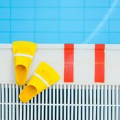 Vibrant yellow swim fins placed by the edge of a clear swimming pool, ideal for aquatic sports.