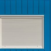 A modern blue wall with a closed white roller shutter, perfect for architectural designs.