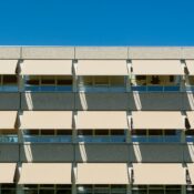 Facade of a modern residential building with sun shades under a clear blue sky.