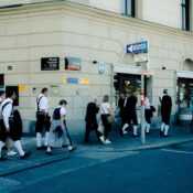 People in traditional attire walk along Herzog-Friedrich-Straße in Innsbruck, Austria.