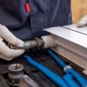 Close-up of a plumber installing a radiator pipe using specialized tools.