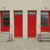 A facade with three vibrant red doors and numbered entrances, located in Berlin.