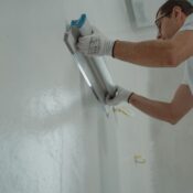 A man works on home renovation, applying plaster to an interior wall for a smooth finish.