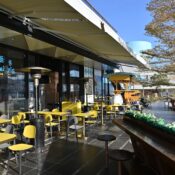 Sunny outdoor cafe with yellow seating and modern decor, ideal for alfresco dining.
