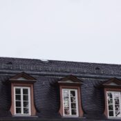 Close-up view of a traditional European building roofline featuring windows and slate roofing.