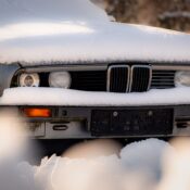 A vintage car parked outdoors, covered in fresh snow in a winter scene in Vienna, Austria.