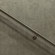 A minimalist image of a stainless steel handrail mounted on a concrete wall.