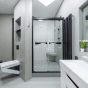 Sink with tap placed at wall with mirror in light spacious bathroom with toilet and glass shower cabin in apartment
