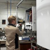 Technician inspects and repairs a heating system in an industrial workshop setting.