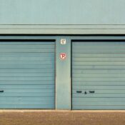 Blue garage doors with a no parking sign painted outdoors.