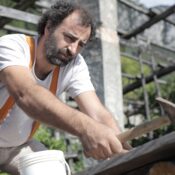 A skilled carpenter attentively uses a hammer during construction work outdoors, showcasing craftsmanship.