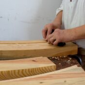 A craftsman shaping wooden planks indoors, focusing on precise woodworking techniques.