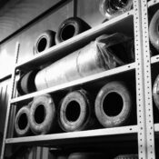 Black and white image of racing tires stored on metal shelves in a warehouse.