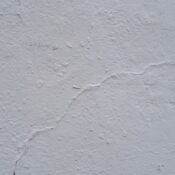 Close-up of a cracked and textured concrete wall surface, ideal for backgrounds or design projects.