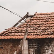An old rural house with a damaged clay tile roof in Chennai, India, showing signs of decay.