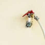 Detailed view of an outdoor water faucet with a bright red handle in Dubai, UAE.