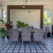 Elegant dining room with Mediterranean style, featuring wicker furniture and lush indoor plants.