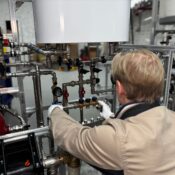 Engineer working on industrial pipe system in a factory for heating and production adjustment.