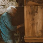 An elderly carpenter working meticulously in a vintage Cairo workshop, crafting wood furniture.
