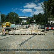 Street construction site in Bratislava with paving stones and machinery under clear blue sky.