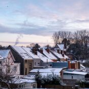 Charming winter scene of snow-blanketed houses in a suburban area with a serene dawn sky.
